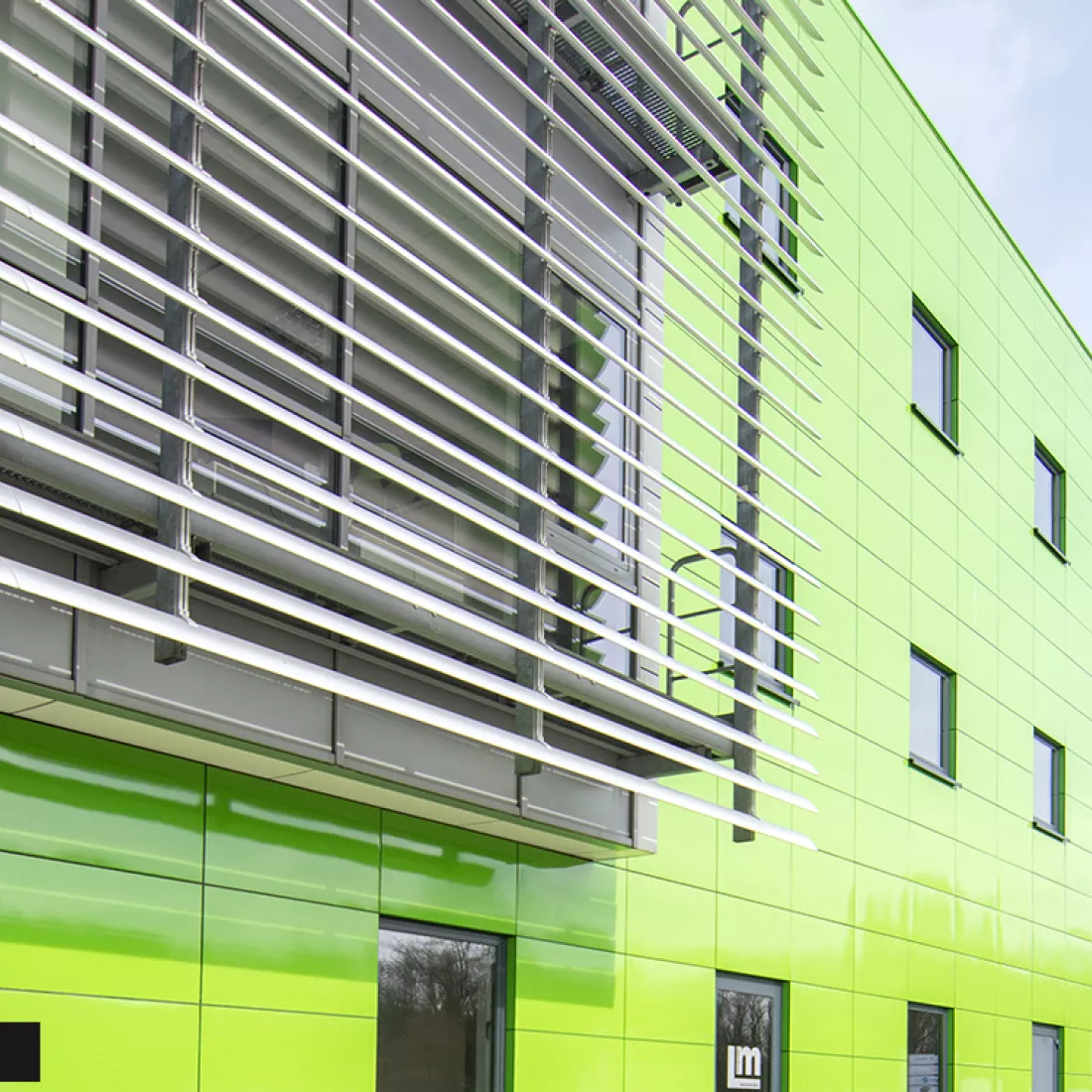 Close-up groene tegels werkgebouw DIBO na renovatie. Het gebouw bevat kleine ramen.