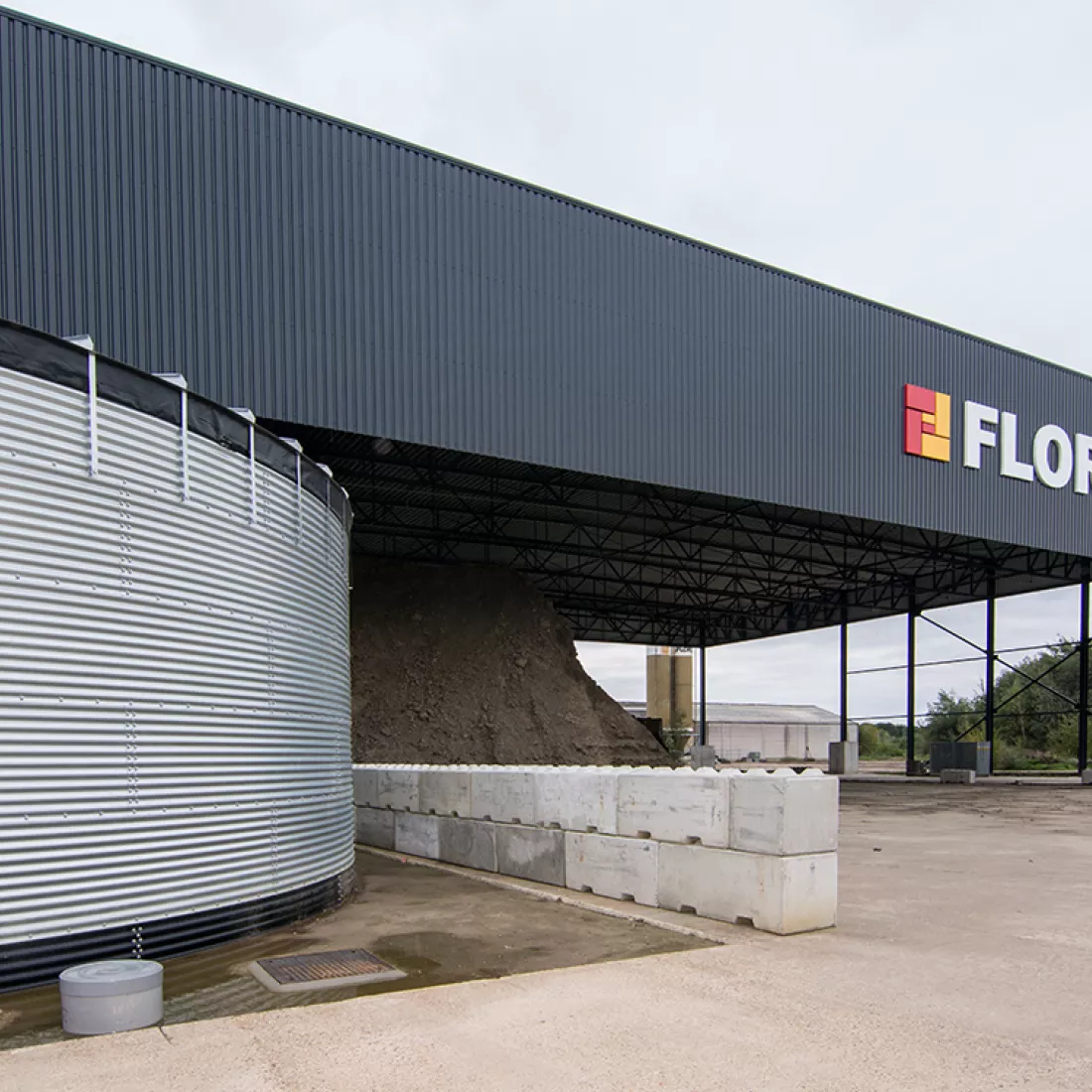 Zijaanzicht luifel kleihal Floren. De luifel is zwart en bevat het logo van Floren.