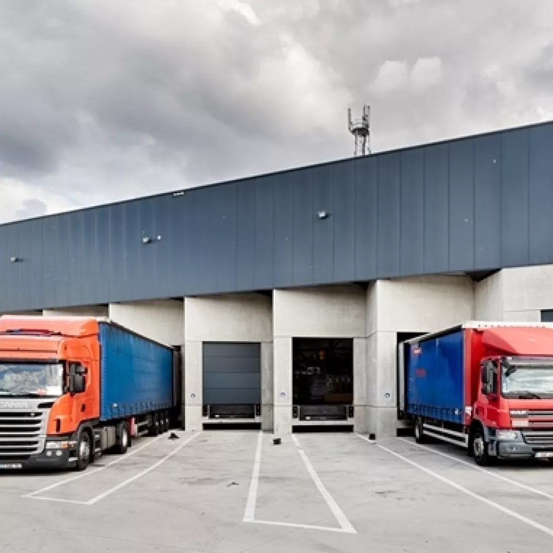 Vooraanzicht dock transitmagazijn Transuniverse. Hier laden en lossen vrachtwagens. De poorten zijn donkergrijs net zoals de bovenkant van het gebouw.