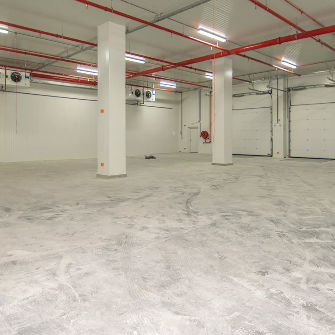 Binnenkant magazijn - Keetberg Logistics Center. Het magazijn is opgebouwd met een combinatie van materialen. Rechts bevinden zich poorten.