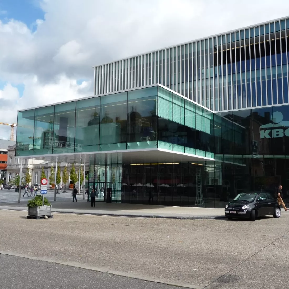 Vooraanzicht kantoor KBC Leuven. Het kantoor bestaat grotendeels uit ramen. Het gebouw bestaat uit drie verdiepingen. Het gebouw werd opgebouwd met staal.