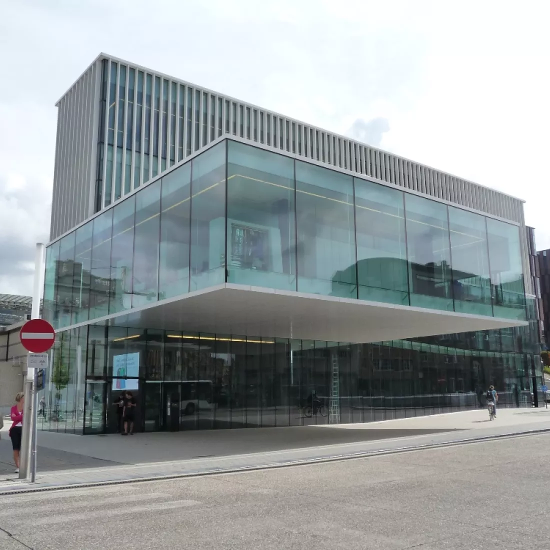 Zijaanzicht kantoor KBC Leuven. Het kantoor bestaat uit grote ramen. Een deel van het tweede verdiep steekt meer naar voren.