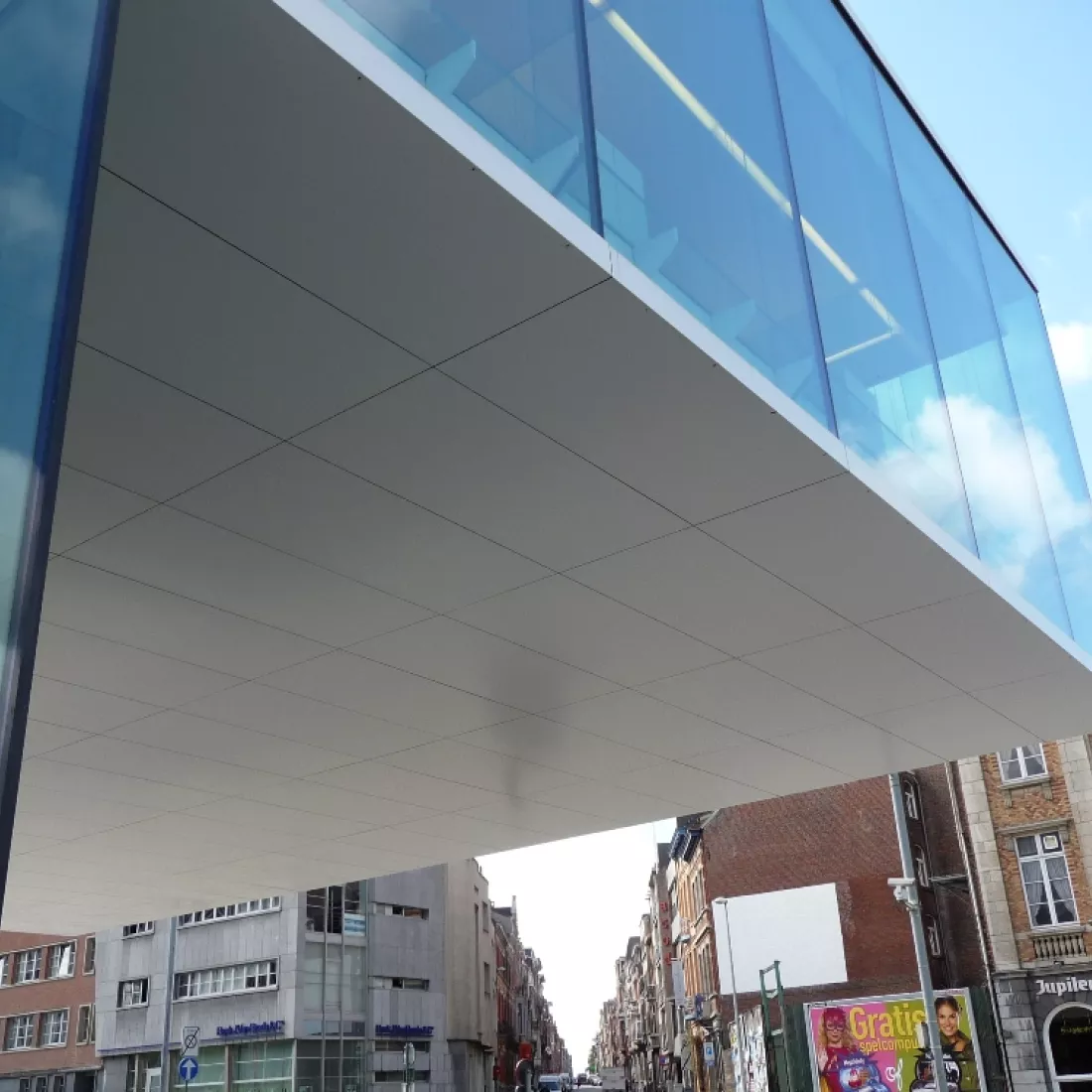 Onderaanzicht tweede verdieping kantoor KBC Leuven. Een deel van de tweede verdieping steekt uit het gebouw. De afbeelding is van de onderkant van dit deel gemaakt. Het bestaat uit witte platen.