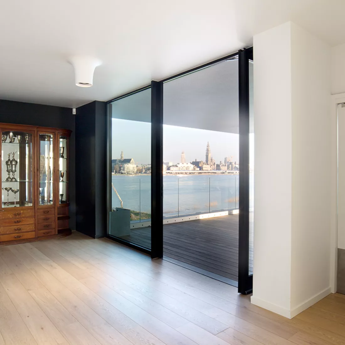 Binnenkant Royal Yacht Club België. Rechts bevindt zich een deur naar het balkon. Vanaf het balkon heb je zicht op de Schelde en de kathedraal. binnen bevindt zich links een kast.