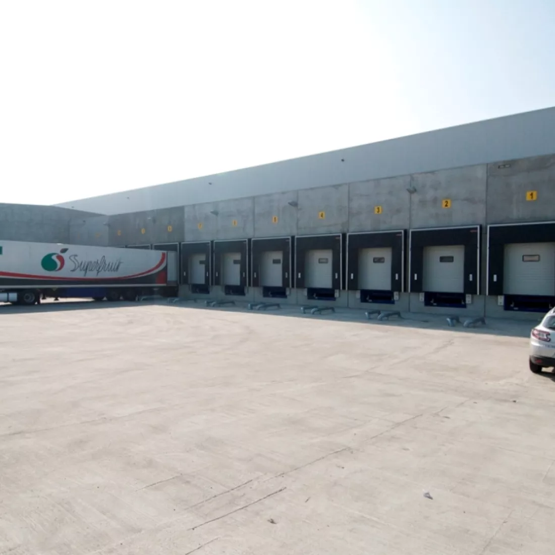 Dock van koelloodsen EFP. Dit is voor het lossen en laden van vrachtwagens. Het gebouw is grijs en bevat witte poorten.