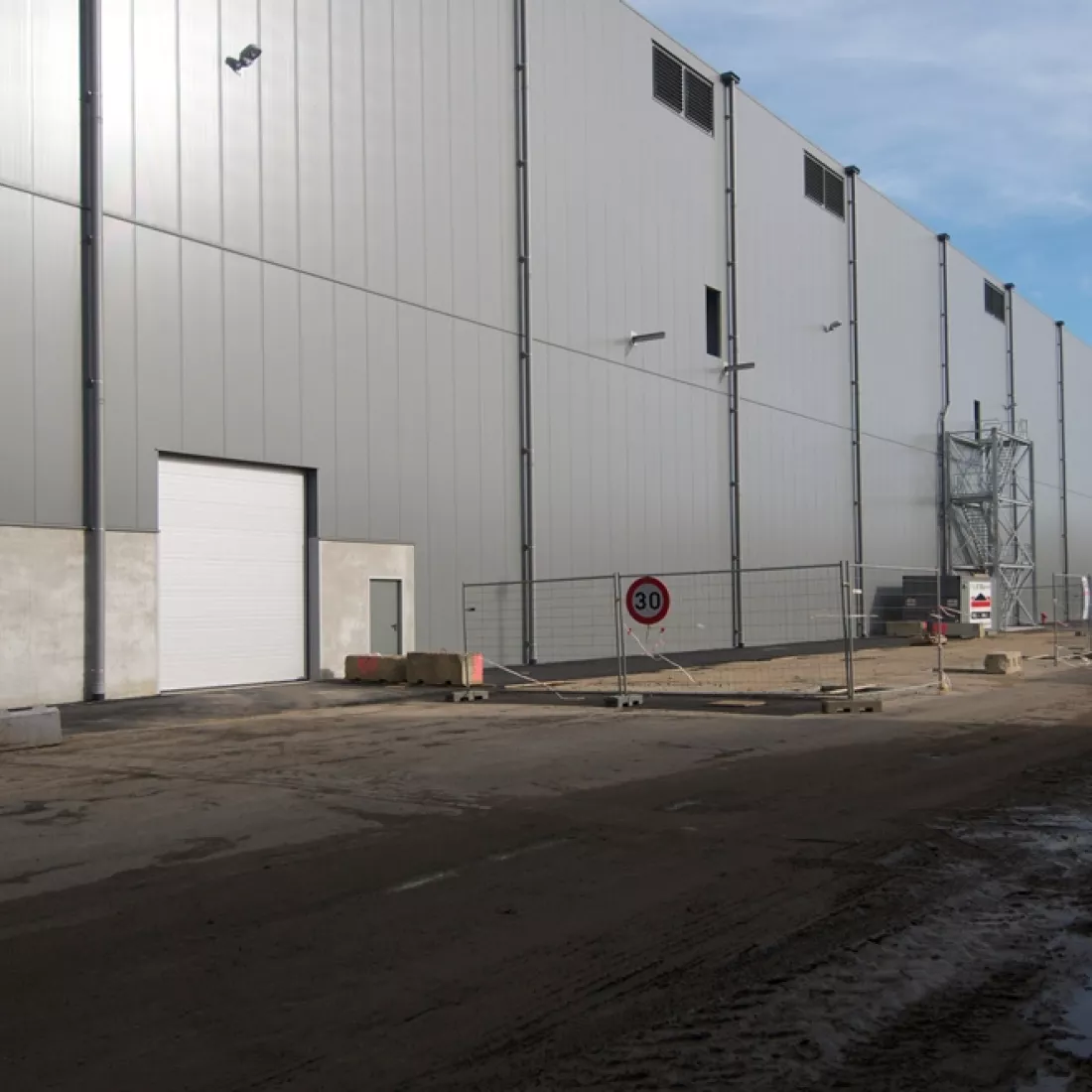 Close-up bulkmagazijn Vollers. Het gebouw is grijs en heeft een witte poort.