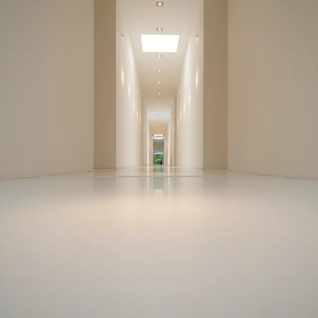 Gang kantoor JNL. Het is een lange witte gang. In het plafond zitten spots.