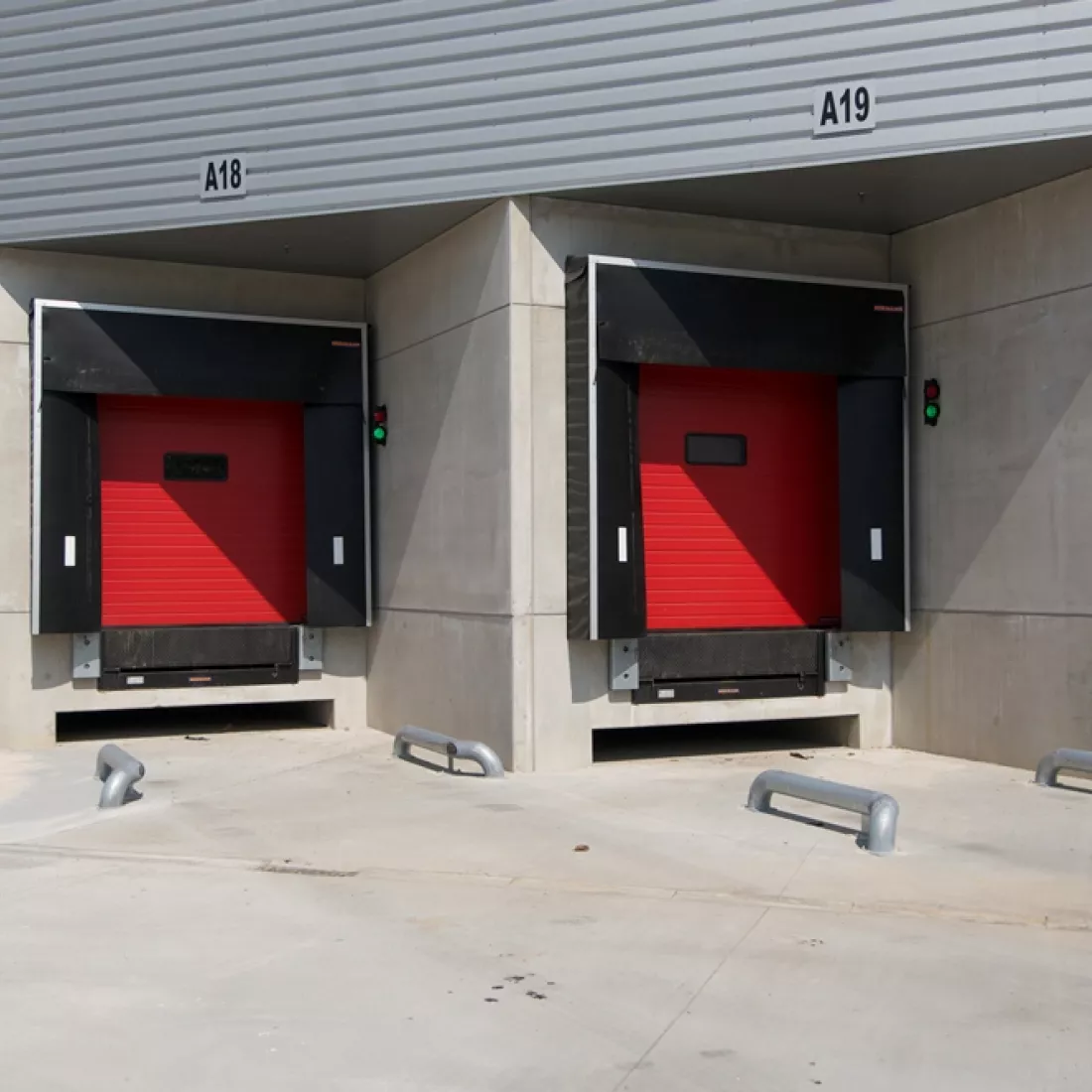 Close-up laadkades ASL & ASL. De poorten zijn rood. Naast de poorten hangen stoplichten. De laadkades bestaan uit beton.