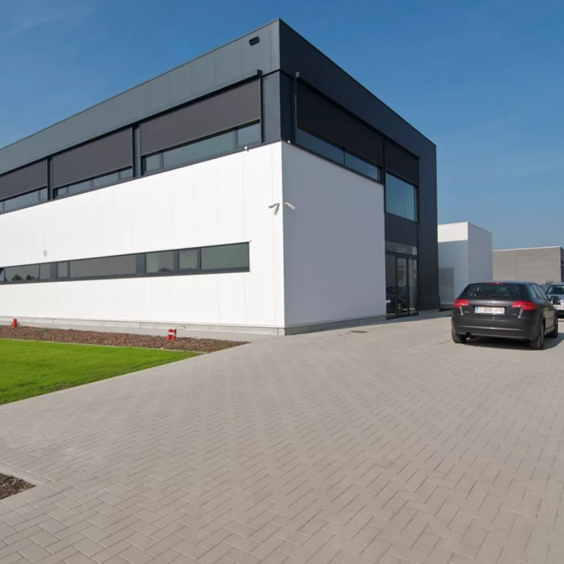  Zijaanzicht productiehal en kantoor Argina. Het gebouw is wit en zwart. Het heeft enkele ramen en twee verdiepen.