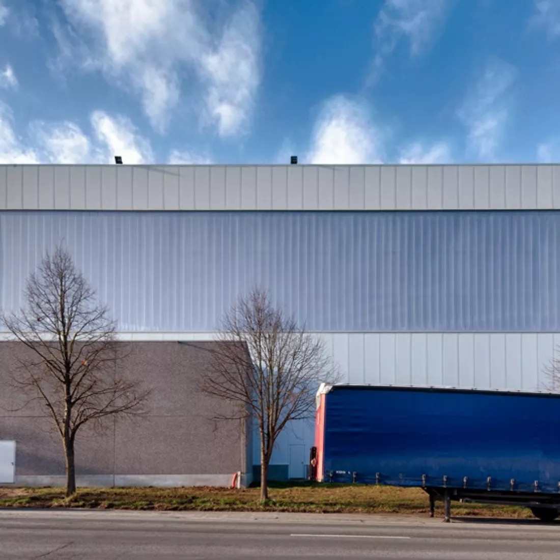 Vooraanzicht opslagplaats - Sabert. Het gebouw is opgebouwd met een combinatie van materialen. Het gebouw is voornamelijk wit, maar ook een deel van het gebouw is grijs.