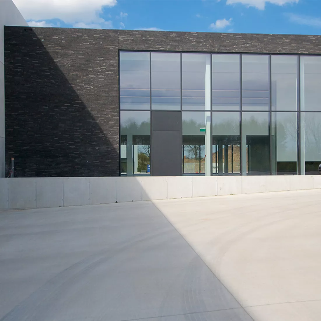 Vooraanzicht kantoor Alcom. Het gebouw bestaat uit zwarte stenen en heeft grote ramen.