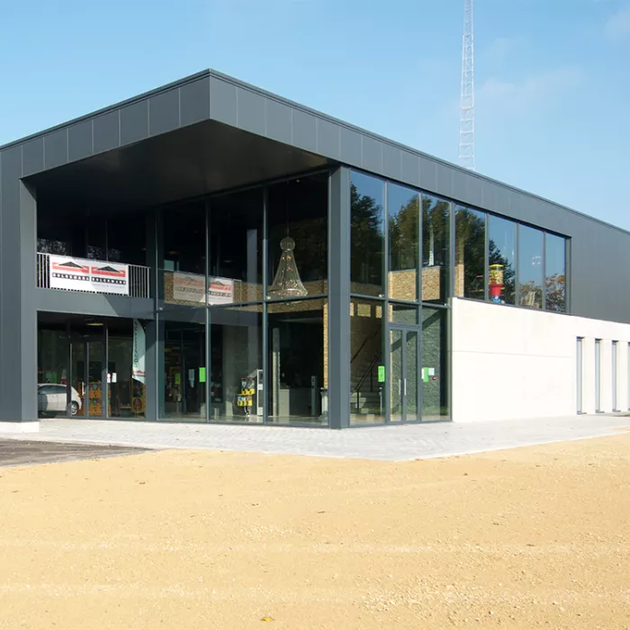 Buitenkant Ice Skating center. Het gebouw heeft een rechthoekige vorm. Een deel van de onderkant van het gebouw is beton. Het andere deel, links op de afbeelding, is zwart net zoals de bovenkant. Het gebouw heeft grote ramen. Tijdens de opbouw van dit gebouw is staal gebruikt.