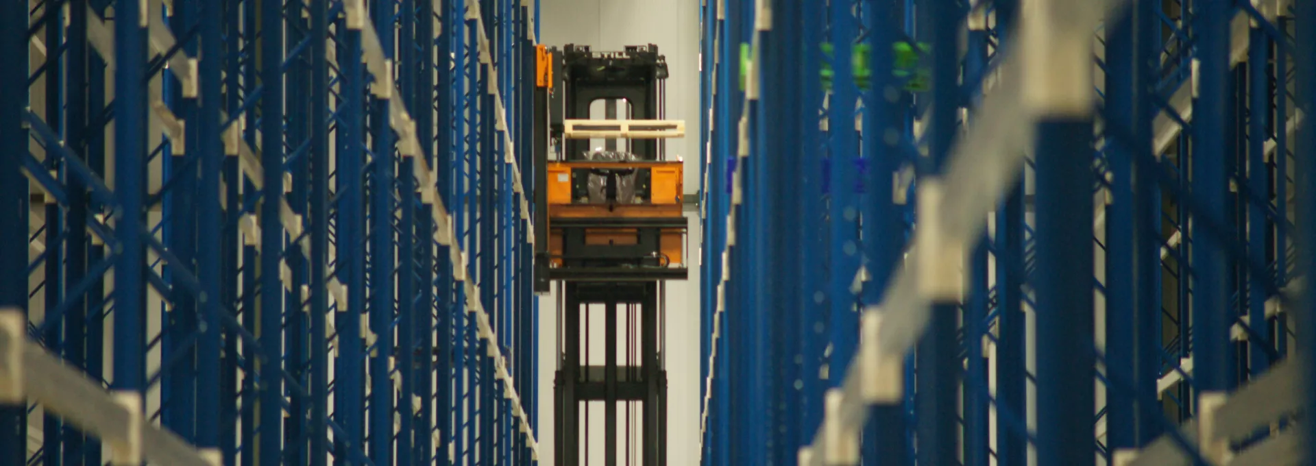 Binnenkant distributiecentrum Miko. Rijen van blauwe rekken met een hoogbouwtruck. Tijdens de opbouw van het gebouw is er staal gebruikt.