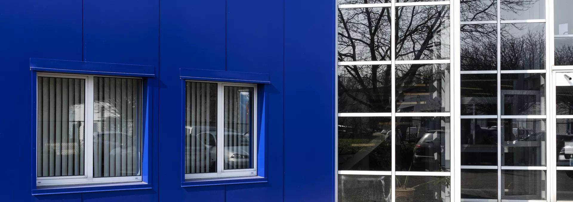 Gevelwijziging en uitbreiding bedrijfsgebouw Syr Oceanic. Het linkerdeel van het gebouw is blauw en bevat enkele ramen met witte omranding. Het rechtergedeelte bestaat alleen maar uit ramen met witte omranding.