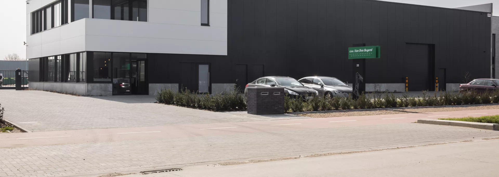 Bedrijfsgebouw Van Den Bogerd. Het is opgebouwd met staal. Het gebouw is zwart met wit. Het bevat ook zwarte poorten, deuren en ramen. Voor het gebouw is parking voorzien.