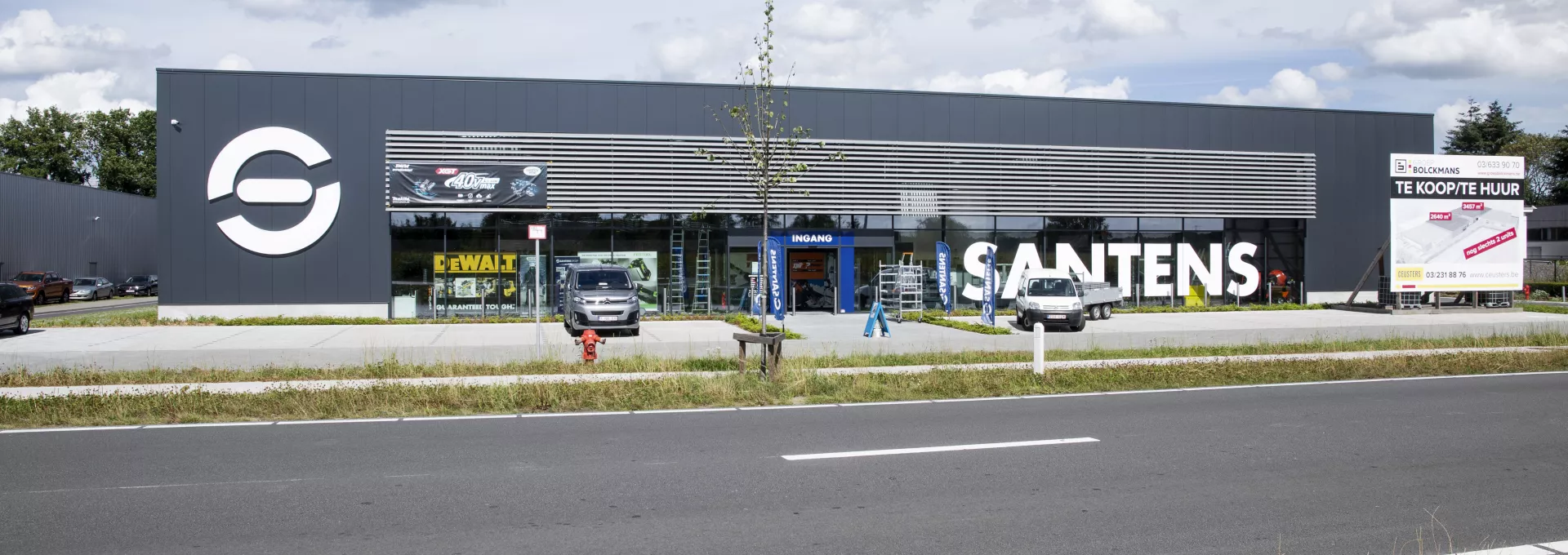 Vooraanzicht bedrijfsunit Immo Bolckmans Geelseweg. Het gebouw is gemaakt uit staal. Het is een zwart gebouw met veel stalen ramen. Voor het gebouw is parking voorzien.