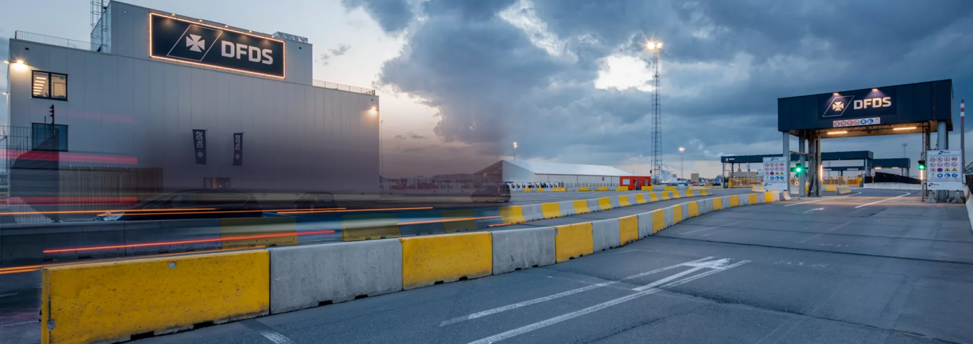 Overzicht werkterrein SEA Invest kantoor DFDS. Links bevindt zich het nieuwe kantoorgebouw. Bij de opbouw is staal gebruikt. Voor het kantoor zijn wegen afgebakend op het werkterrein met grijze en gele betonblokken.