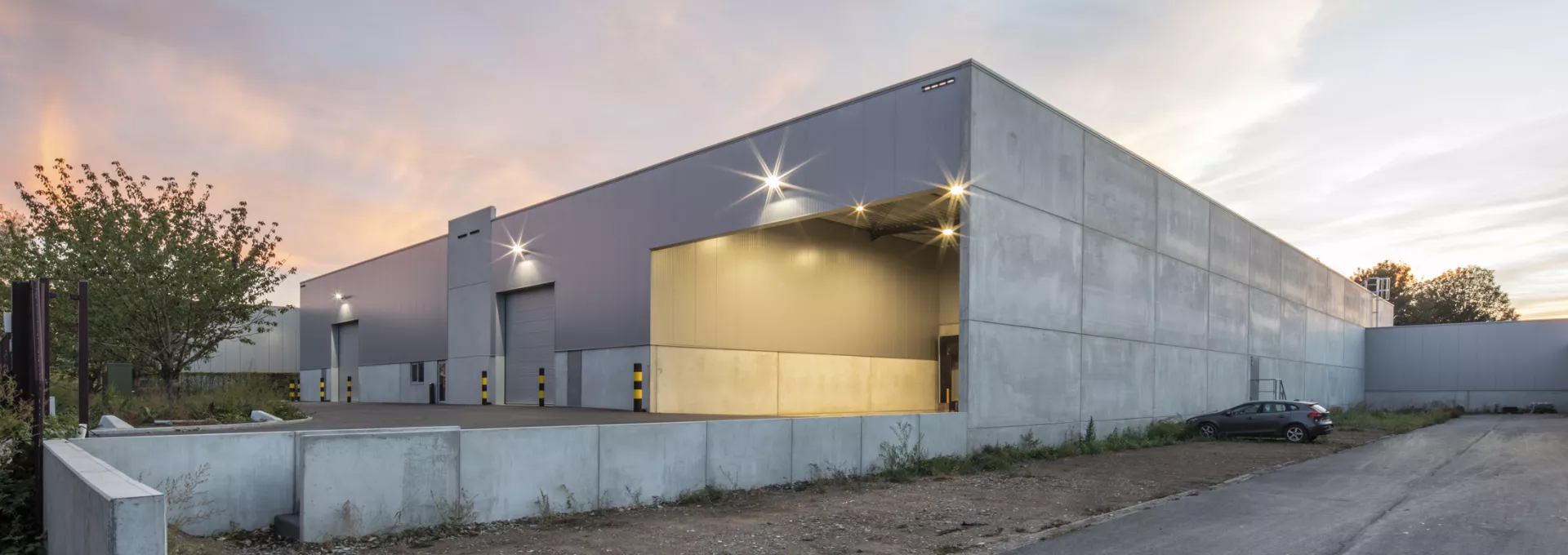 Zijaanzicht magazijn Corpack en doorgang naar bestaande productiehal. Het gebouw is grijs en bij de opbouw is staal gebruikt.