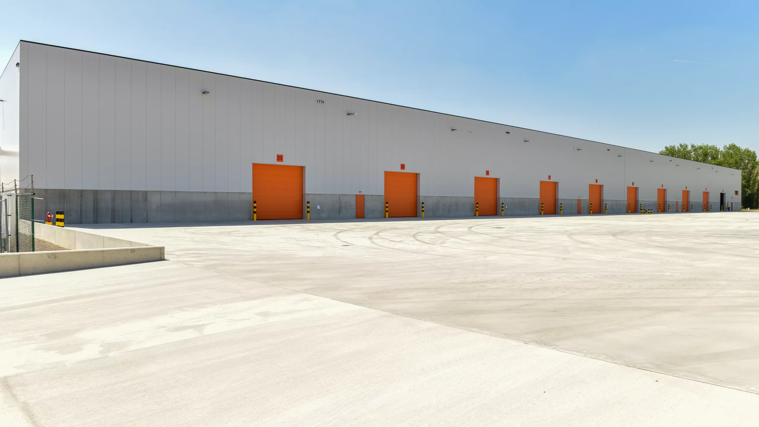 Buitenkant Promat hal 9. Het is een grijs gebouw met oranje poorten.