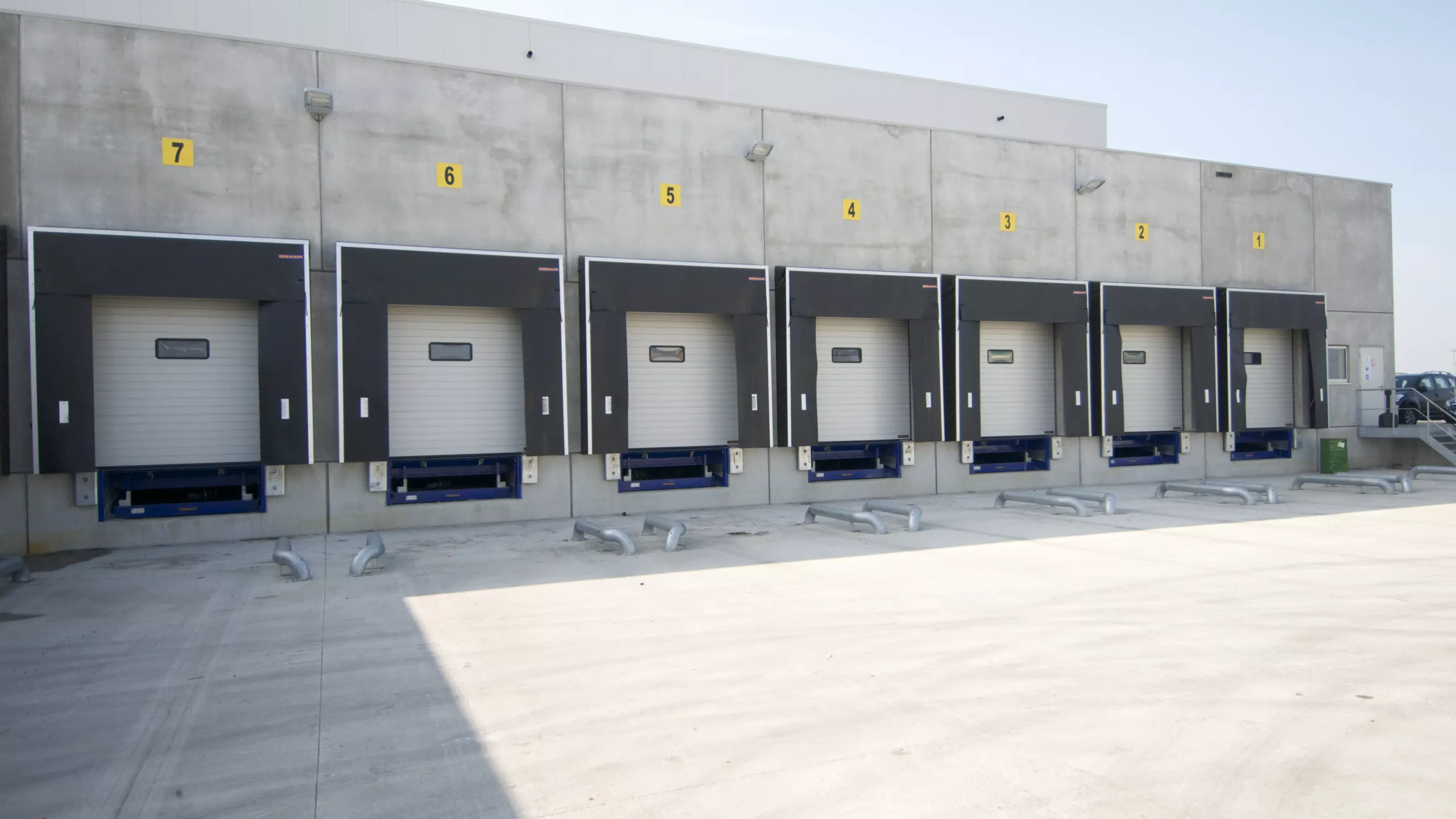 Dock van koelloodsen EFP. Dit is voor het lossen en laden van vrachtwagens. Het gebouw is grijs en bevat witte poorten.