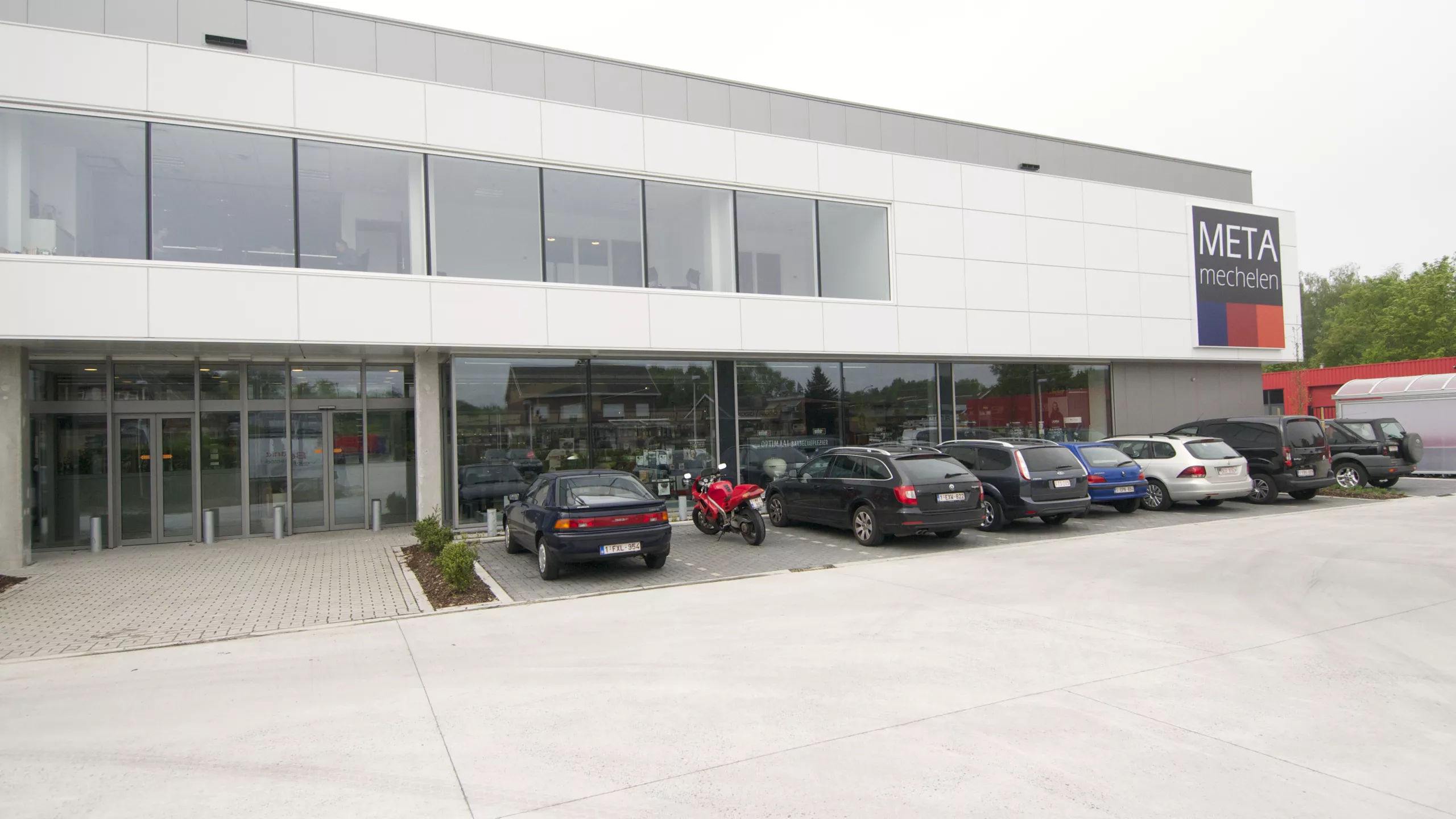 Werkplaats, magazijn en kantoor - METALeuven. Voor het gebouw zijn parkeerplaatsen voorzien. Het gebouw is opgebouwd met een combinatie van materialen.