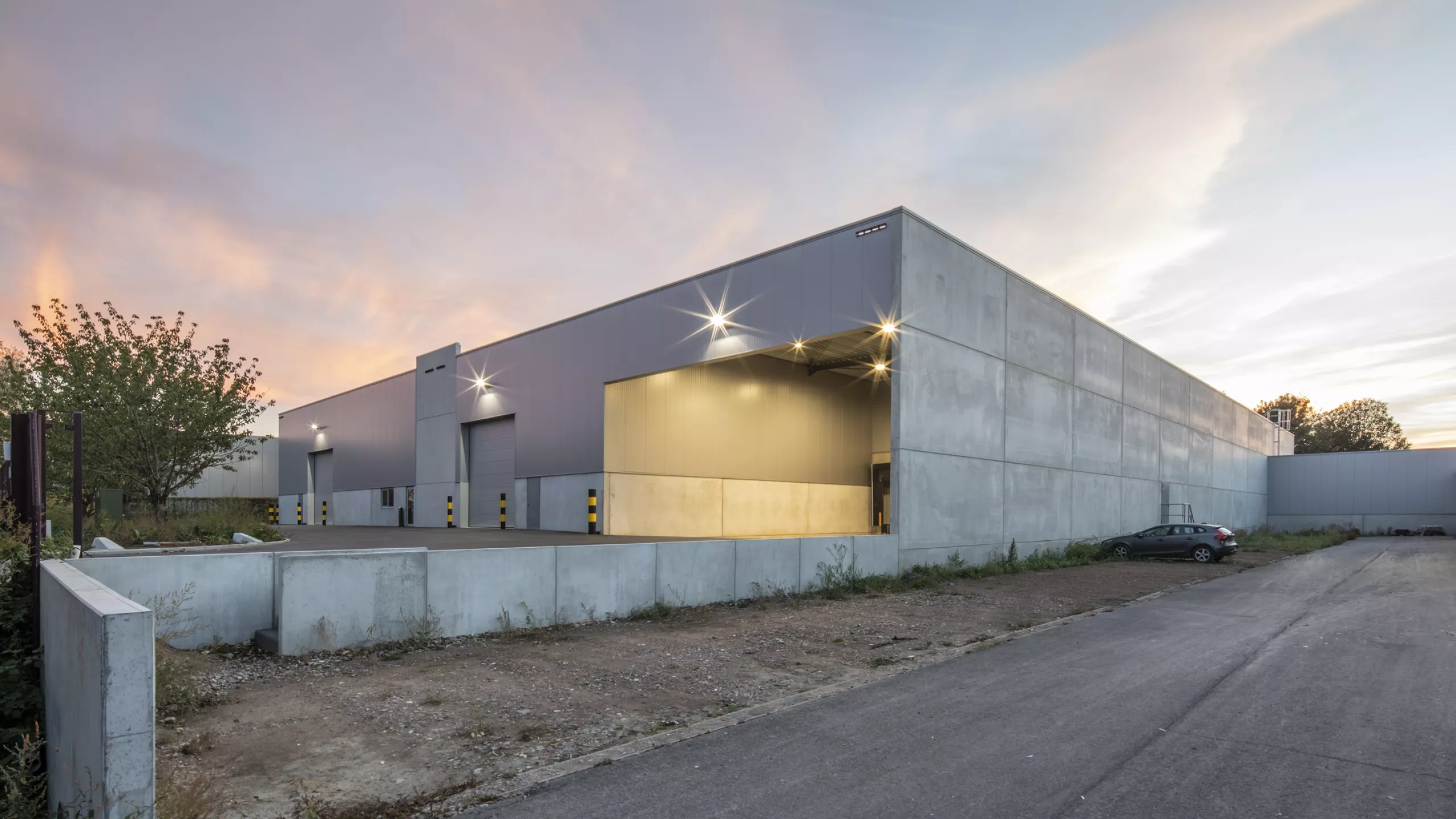 Zijaanzicht magazijn Corpack en doorgang naar bestaande productiehal. Het gebouw is grijs en bij de opbouw is staal gebruikt.