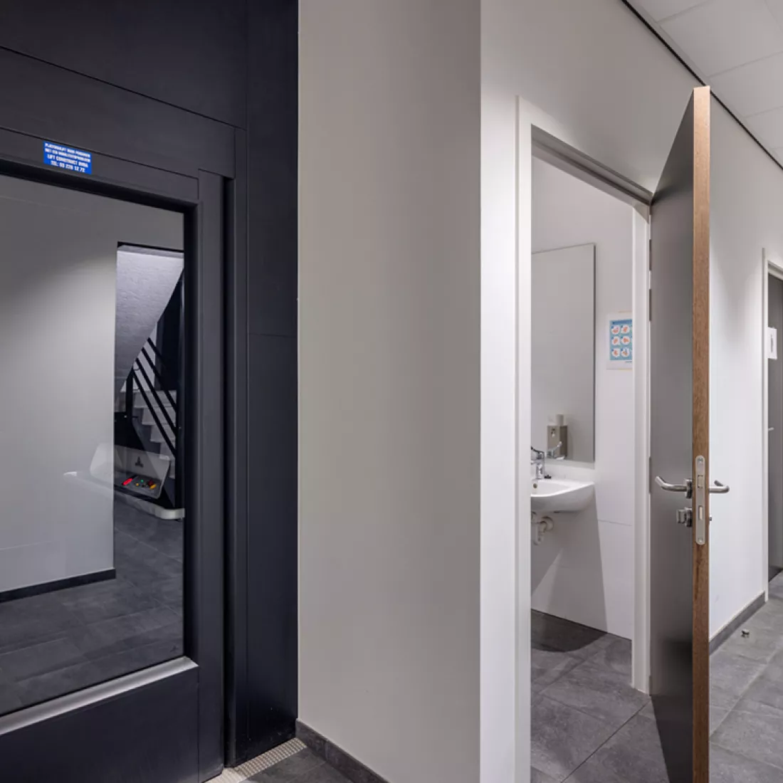 Binnenkant van de toiletruimte van het opslagmagazijn van Bauwens Logistics. Rechts zijn er toiletten. links is een zwarte deur.