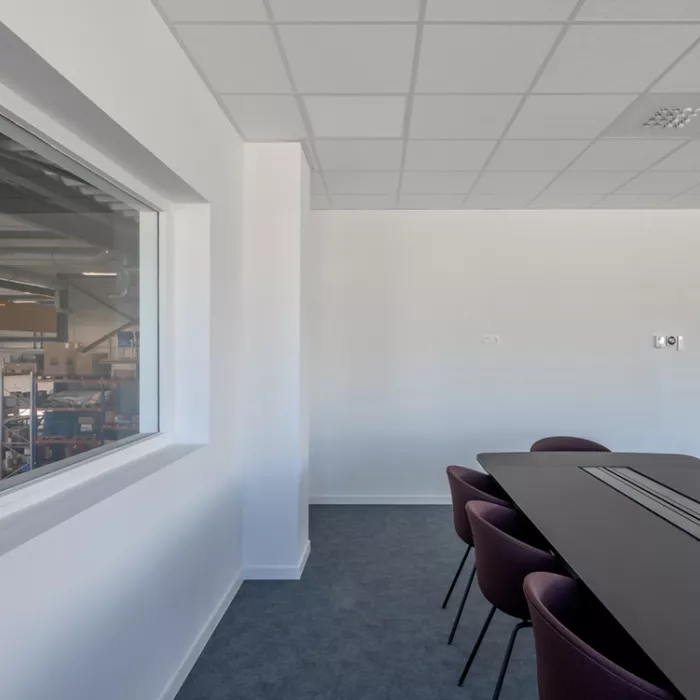 Binnenkant vergaderruimte in het gebouw van Terberg Gent. De muren zijn wit. In het midden staat een zwarte rechthoekige tafel met stoelen rond.