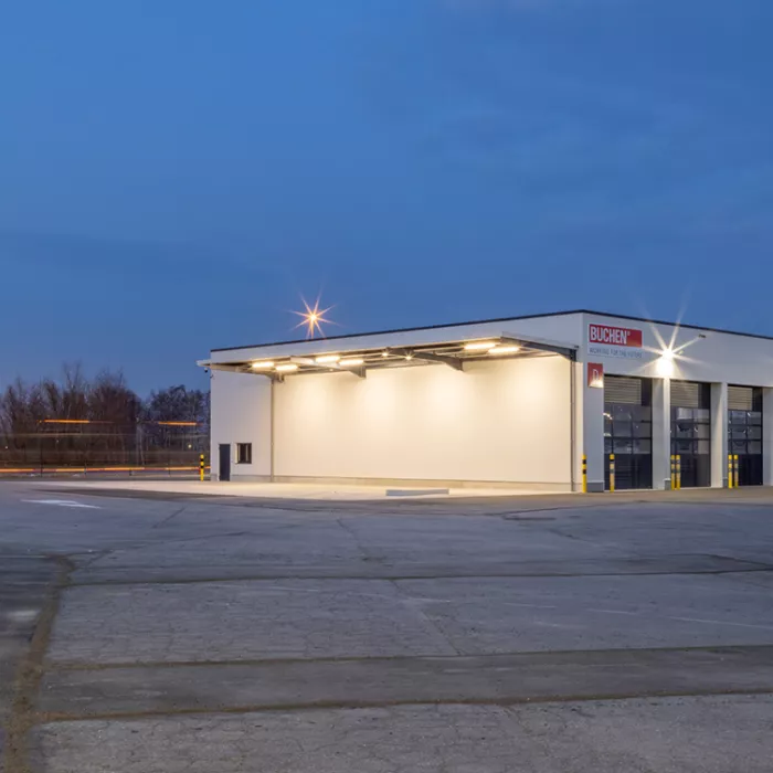 Zijaanzicht industrieel gebouw Xervon. Het is een wit gebouw waarbij staal is gebruikt voor de opbouw. Het gebouw bevat donkerblauwe poorten.