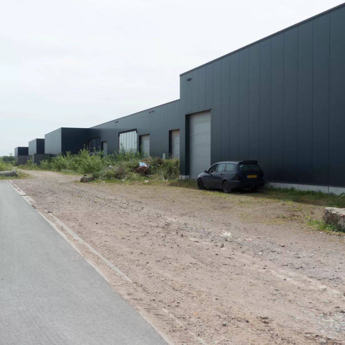 KMO Units Picolo - Van Ende. De units zijn opgebouwd uit een combinatie van materialen. Langs de buitenkant bestaan de units uit zwarte platen en grijze poorten.