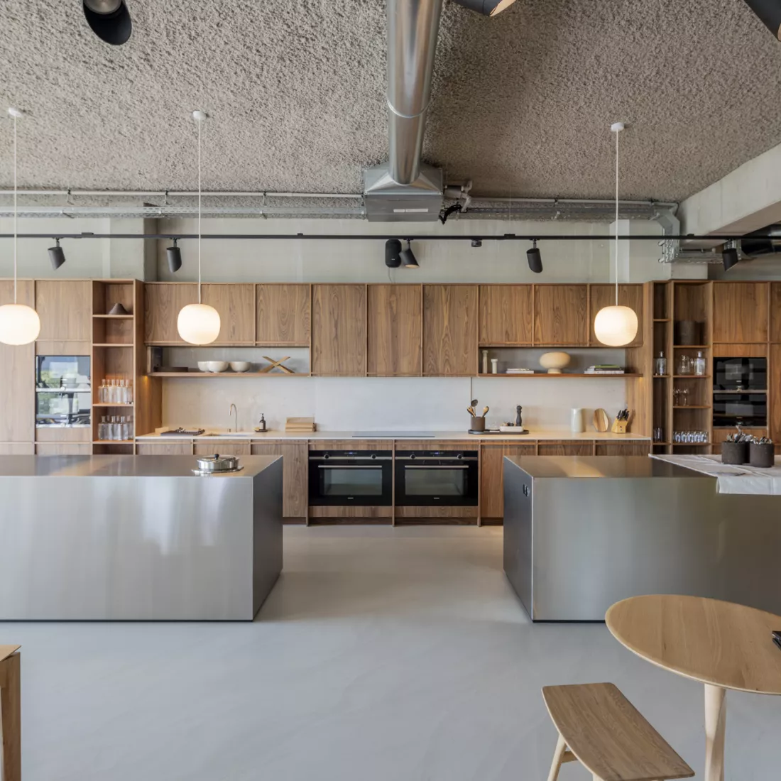 Binnenkant kantoor Ethnicraft - keuken. Achteraan bevindt zich een keuken in houtlook. Voor de keuken staan twee keukeneilanden.