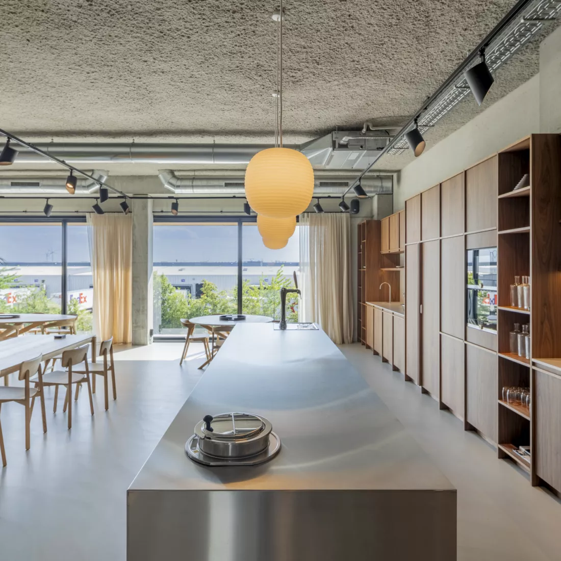 Binnenkant kantoor Ethnicraft - keuken en refter. Rechts bevindt zich de keuken en links bevinden zich tafels en stoelen. Achteraan bevinden zich grote ramen.