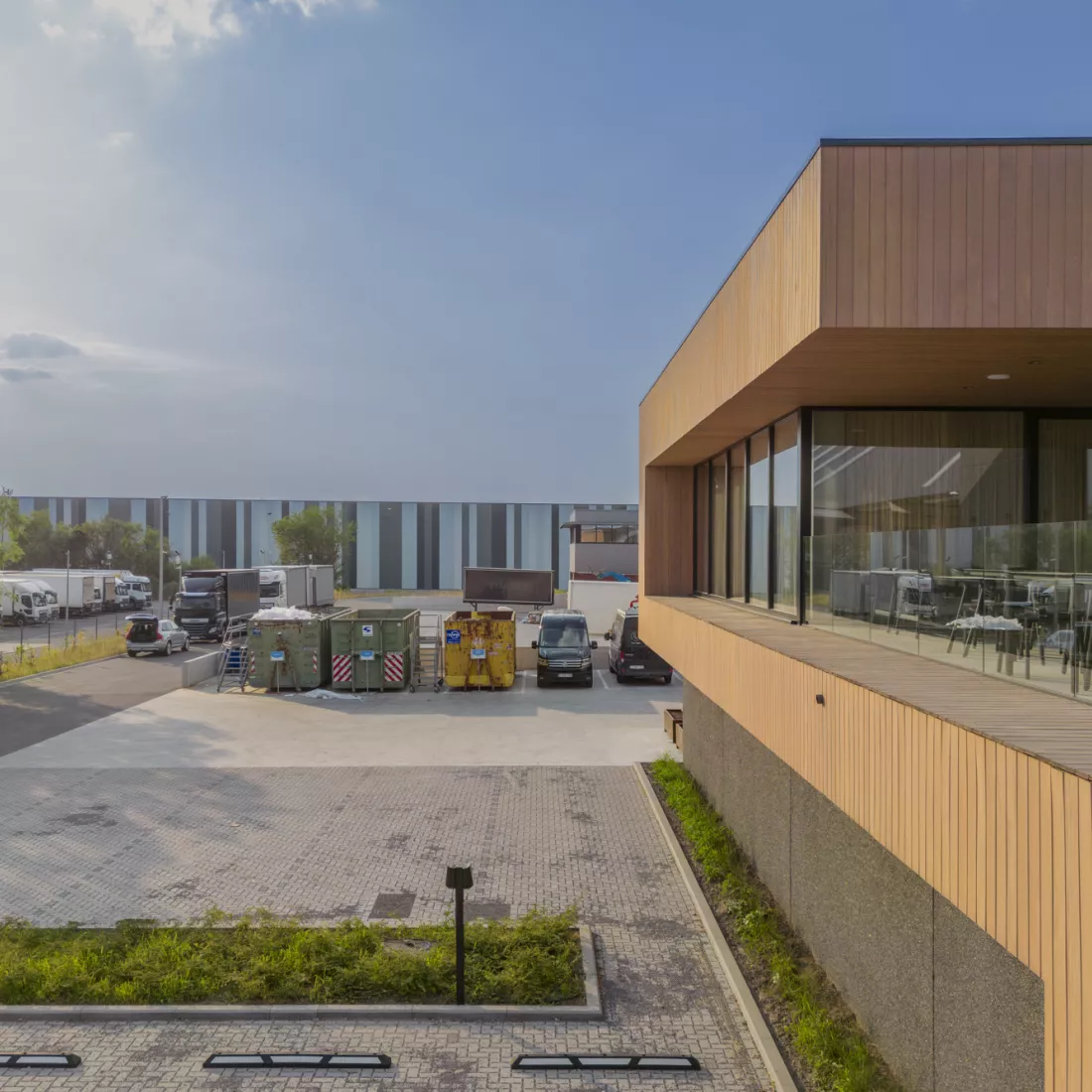Zijaanzicht Ethnicraft. Rechts bevindt zich het gebouw met de houtlook. Links bevindt zich parking.
