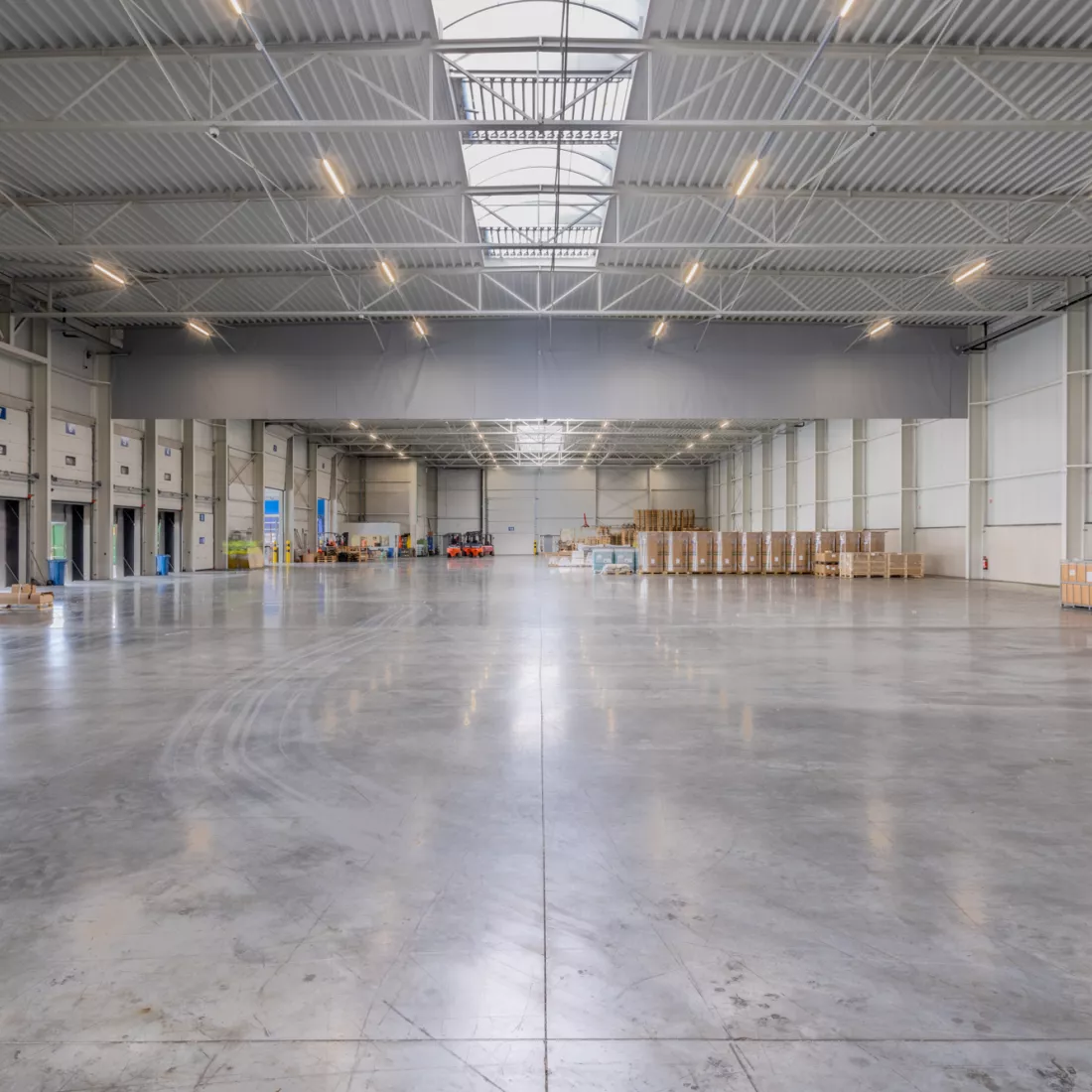 Binnenkant magazijn Scanfor. Links bevinden zich de poorten. Links vanachteren staan heftrucks en rechts opgeslagen materiaal.