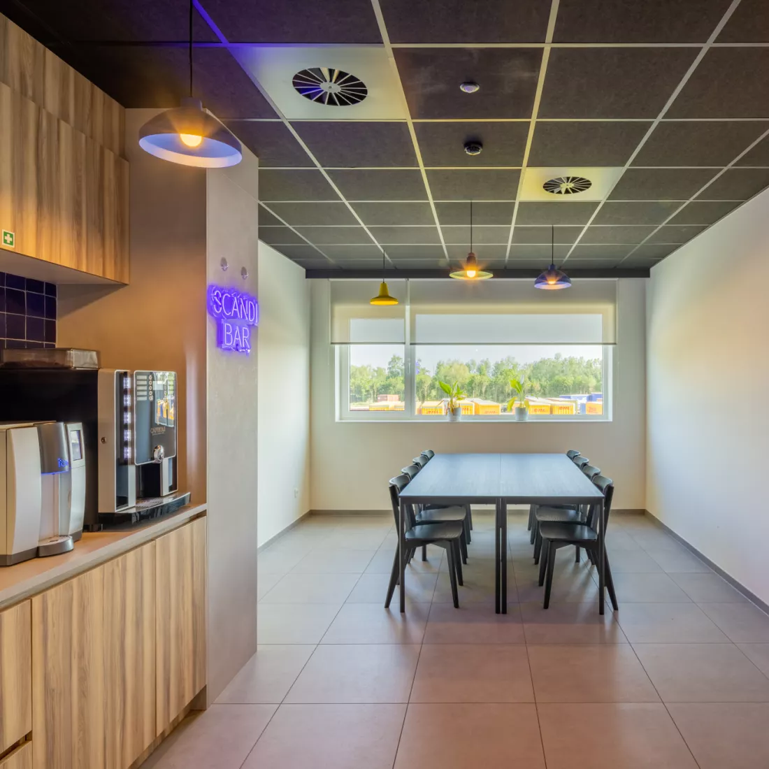 Lunchruimte in het kantoor van Scanfor. Links bevinden zich keukenkasten met koffieapparatuur op. In het midden staat een tafel met stoelen rond. Achteraan is een raam.