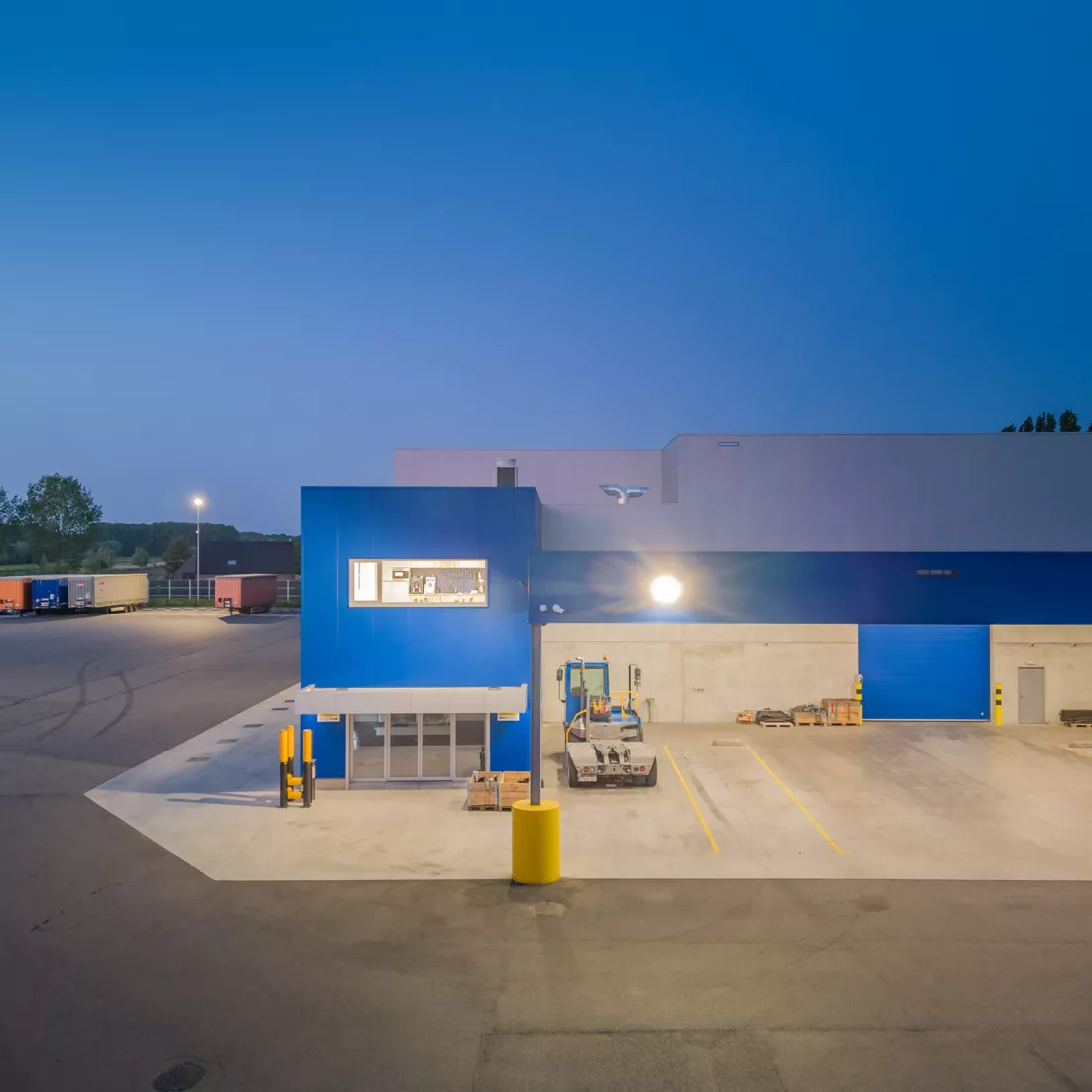 Hoger vooraanzicht kantoor en magazijn Scanfor. Het kantoor is blauw en het magazijn grijs met blauwe details, zoals een blauwe poort.