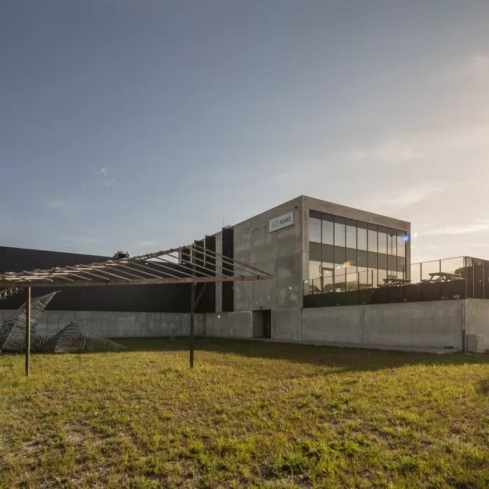 Zijaanzicht sorteer- en recyclagecentrum - Sita kantoor & garage. Links bevindt zich de garage en rechts het kantoor. Het gebouw bestaat uit drie verdiepingen en bevat een balkon.