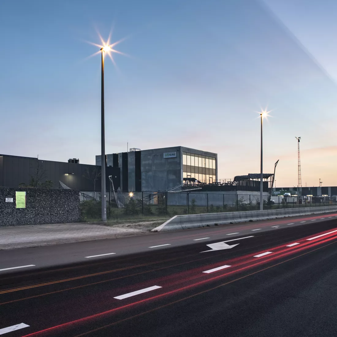 Zijaanzicht sorteer- en recyclagecentrum - Sita kantoor & garage. Het gebouw bevindt zich links van de baan. Tijdens de opbouw is er een combinatie van verschillende materialen gebruikt.