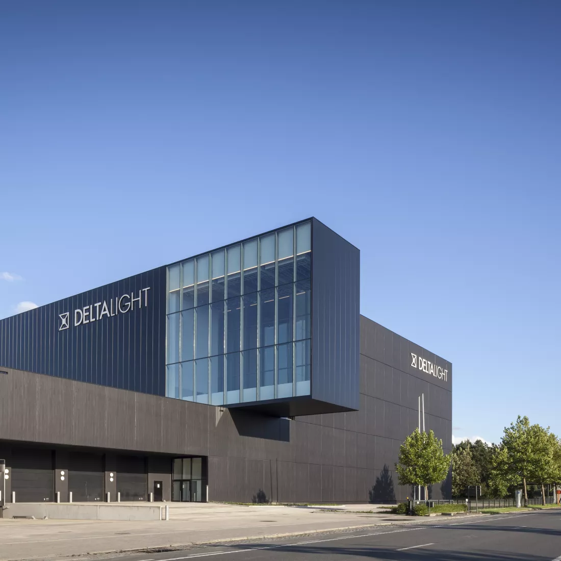 Gebouw Delta Light. Het gebouw bestaat uit zwarte platen. In het midden steekt een deel van het gebouw meer naar voren. Het voorste deel hiervan bestaat uit ramen. Links op dit deel van het gebouw hangt het logo van Delta Light.