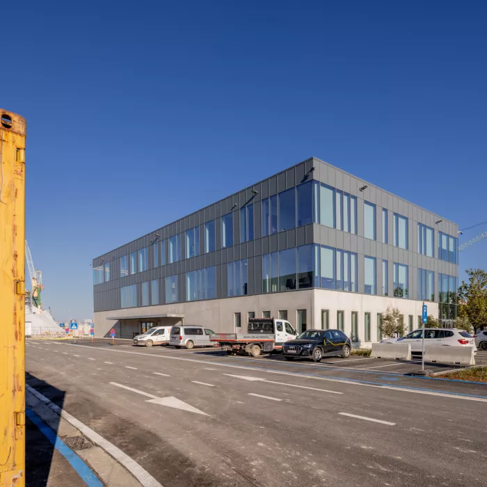 Zijaanzicht kantoor EDR. Het kantoor bestaat uit drie verdiepingen. Het gebouw bevat veel ramen. De bovenste twee verdiepingen bestaan uit zwarte platen.