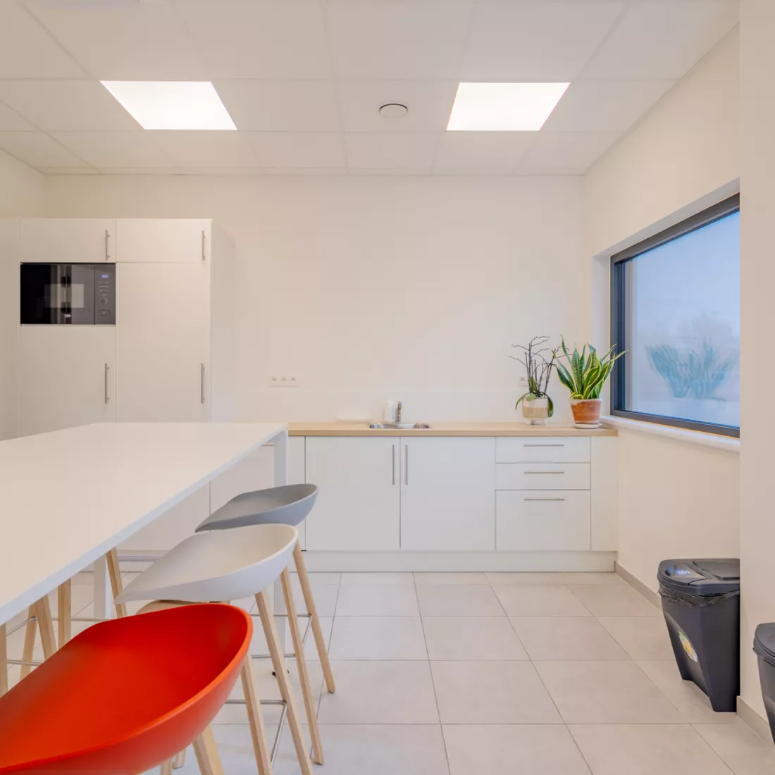 Keuken van het kantoor. Witte keuken met hoge tafel en gekleurde barkrukken.