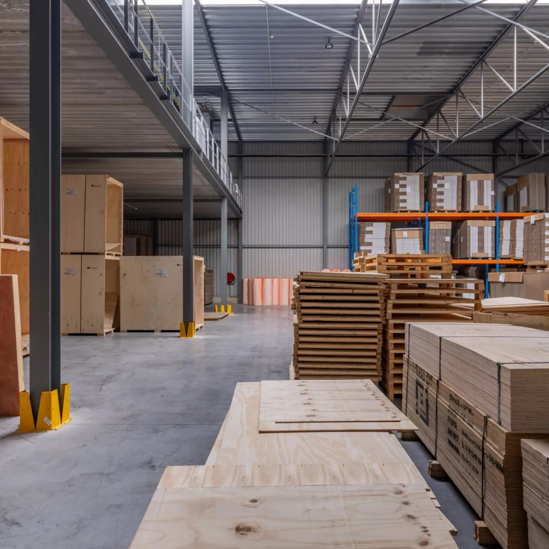 Magazijn van Putters-Move Relocation gemaakt uit staal. Er staan allemaal houten kisten op elkaar gestapeld. Ook liggen er kartonnen dozen. Er staat vanachter één rek waar hun materiaal ook in wordt opgeslagen.