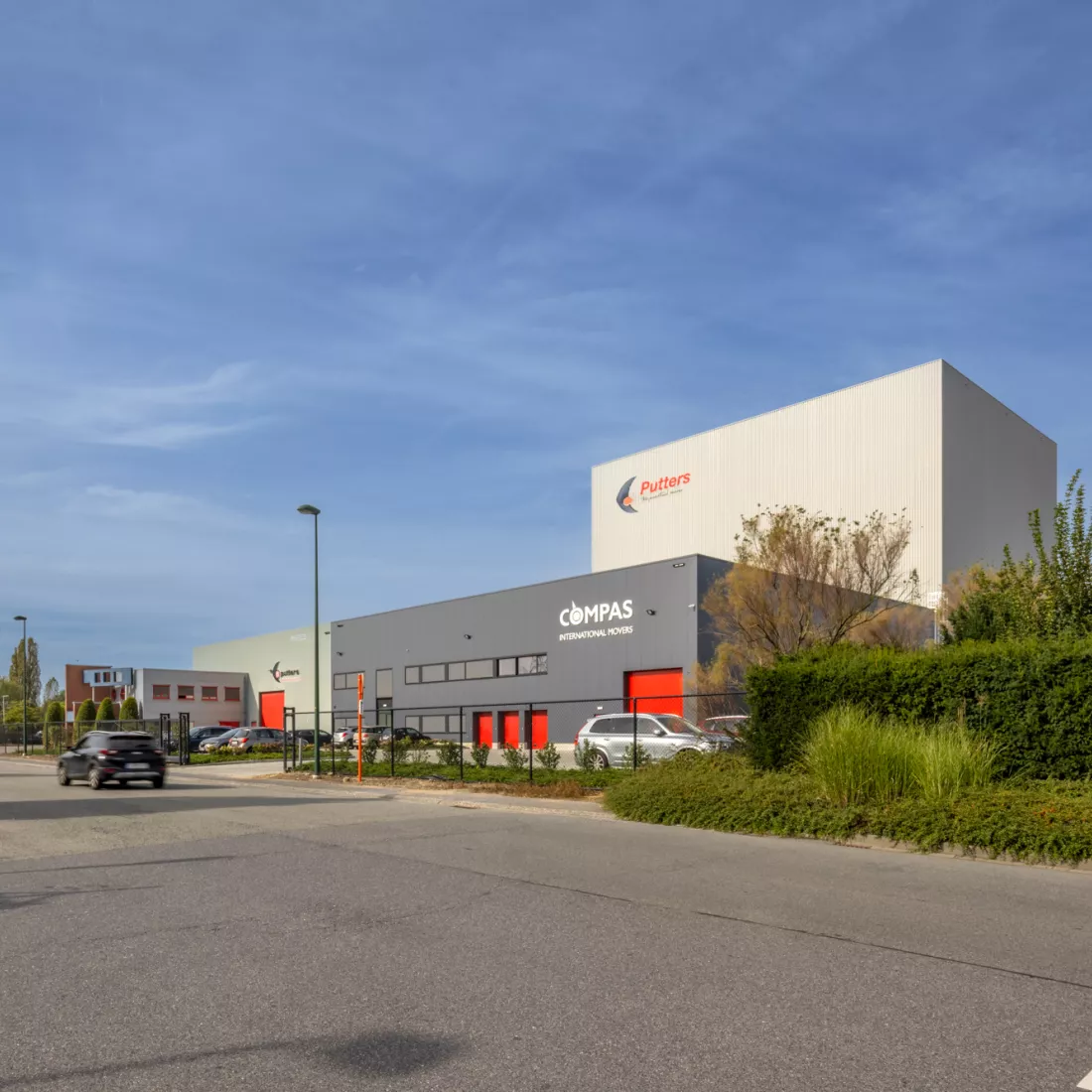 Volledig overzicht over het kantoor en magazijn van Putters-Move Relocation gemaakt uit staal. Het kantoor is grijs met rood accent van de poorten.