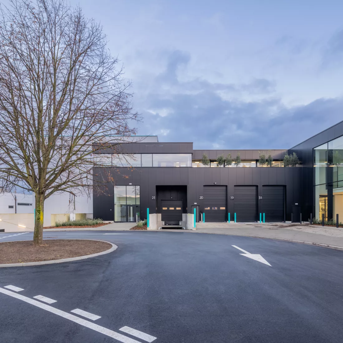 Vooraanzicht industrieel gebouw Reynders Pharma. Het gebouw bestaat uit zwarte en witte platen. Het gebouw heeft twee verdiepingen. Het gebouw bestaat uit beton.