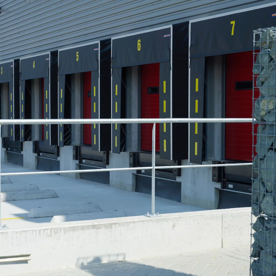 Close-up laadkades Prologis. De poorten zijn rood met zwarte omranding. Op de zwarte omranding staan gele strepen en de nummer van de poort.