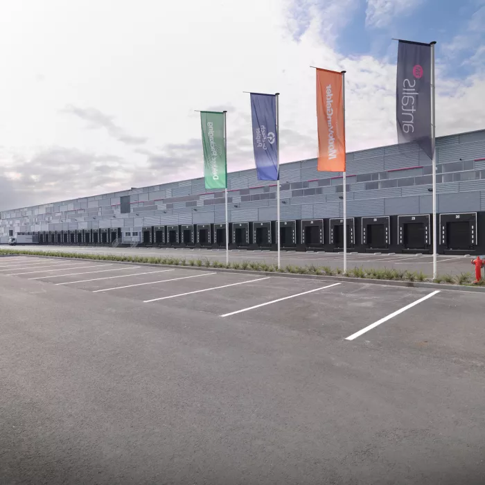 Laadkades of dock magazijn Prologis Almere - Antalis. Dit is voor het laden en lossen van vrachtwagens. De poorten zijn zwart. Voor het magazijn is een parking met witte afgebakende lijnen. Hierbij hangen vlaggen van Antalis.