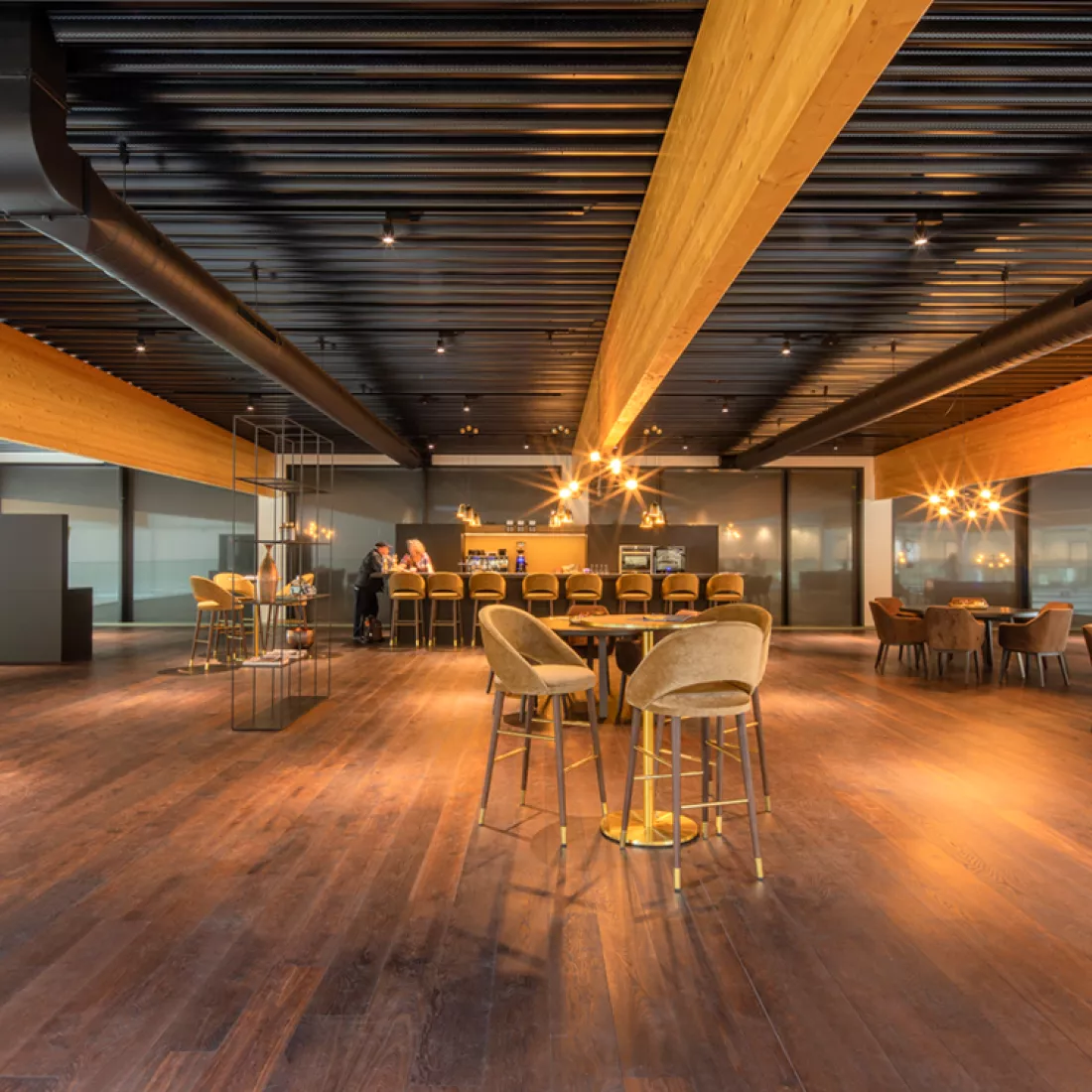 Garage Van Hoecke interieur. Achteraan bevindt zich een bar met barkrukken aan. Er staan ook verschillende tafels met verschillende stoelen.