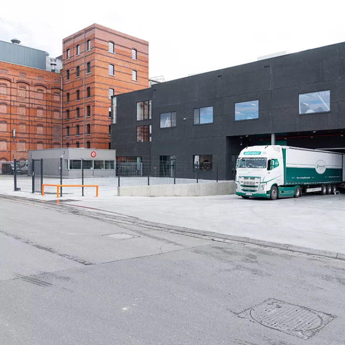 Zijaanzicht magazijn Dossche Mills. Rechts staat er een vrachtwagen in het dock. Het gebouw is zwart en bevat grote ramen.