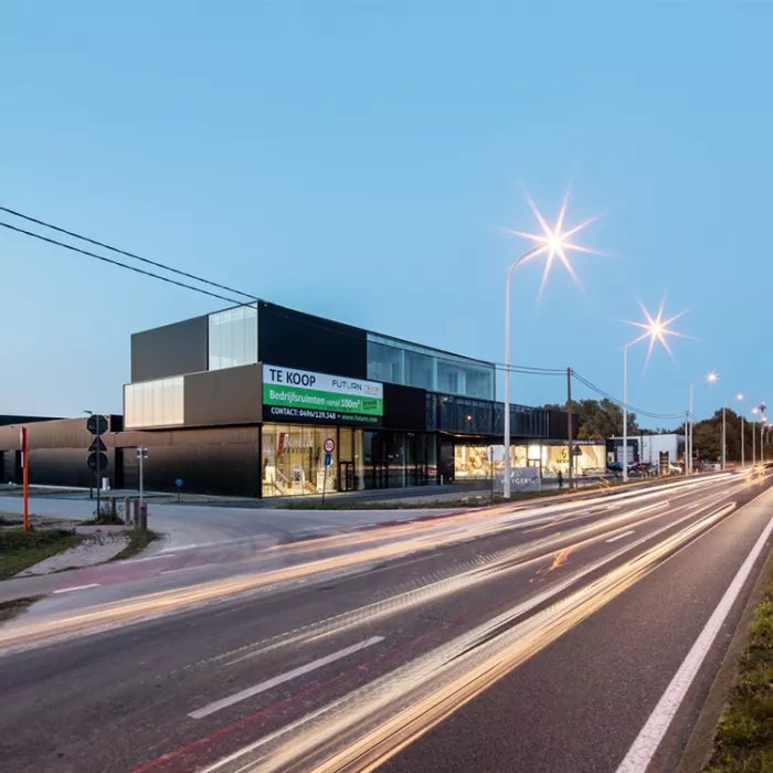 Zijaanzicht bedrijfsunits Futurn. De bedrijfsunits zijn gemaakt uit staal en bevat drie verdiepingen. De foto is gemaakt vanaf de overkant van de straat. Het gebouw is zwart en bevat veel ramen.