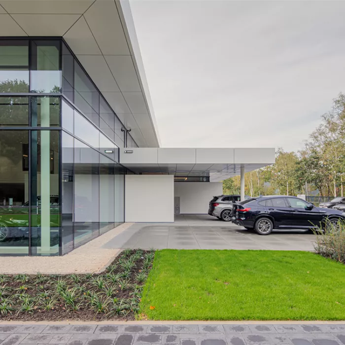 Close-up showroom garage Meeusen. Het gebouw is wit en heeft grote ramen.